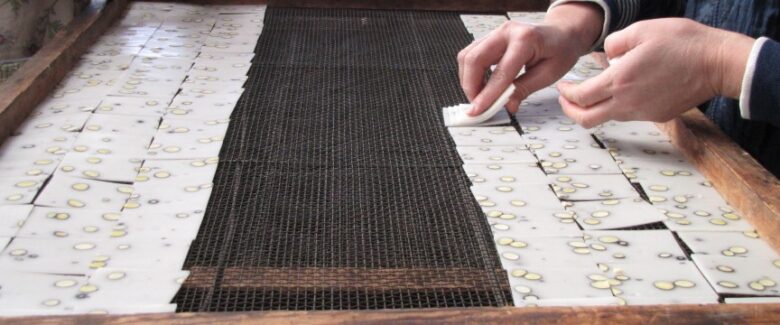 米菓の生地を天日乾燥させるために専用網に並べる様子（撮影写真）